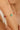 Close-up of a person's arm wearing a gold bracelet with green and red beads.