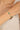 Gold bracelet with green beads on a wrist against a neutral background