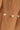 Gold bracelet with pearls on a wrist against a neutral background