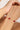 Gold bracelet with red gemstones on a wrist against a white background