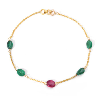 Gold bracelet with green and red gemstones on a white background