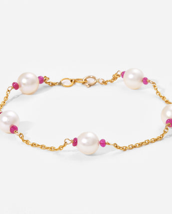 Pearl bracelet with gold chain and pink beads on a white background