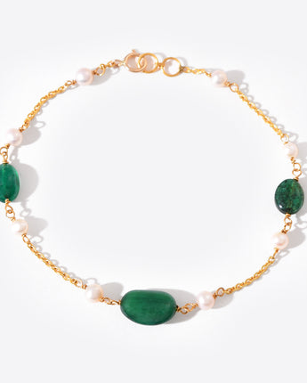 Bracelet with gold chain, green beads, and white pearls on a white background