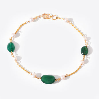 Bracelet with gold chain, green beads, and white pearls on a white background