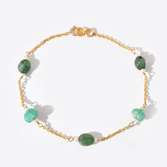 Gold bracelet with green gemstones on a white background