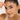 Woman holding a bracelet on her face with a plain background