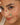 Close-up of a woman's face with a decorative bracelet featuring gemstones.