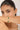 Woman wearing a gold bracelet with green stones on a neutral background