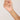Hand holding a delicate gold necklace with small colored beads against a plain background