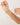 Hand holding a delicate gold necklace with green beads against a light background