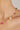 Gold necklace with pink and white beads on a woman's neck against a neutral background