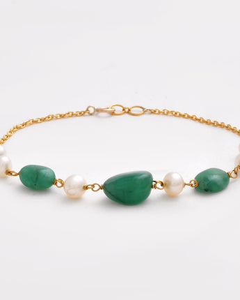 Bracelet with green stones and pearls on a gold chain against a white background