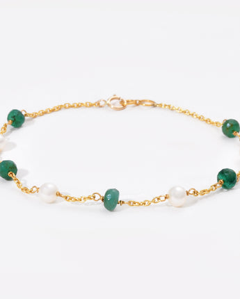 Bracelet with green gemstones and gold chain on a white background