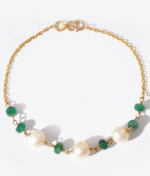Bracelet with gold chain, green gemstones, and pearls on a white background