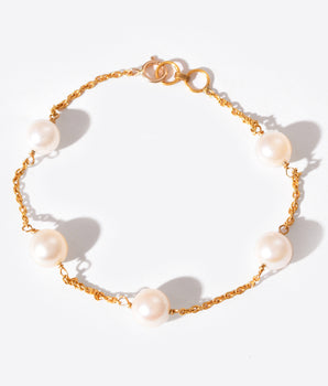 Gold chain bracelet with pearls on a white background